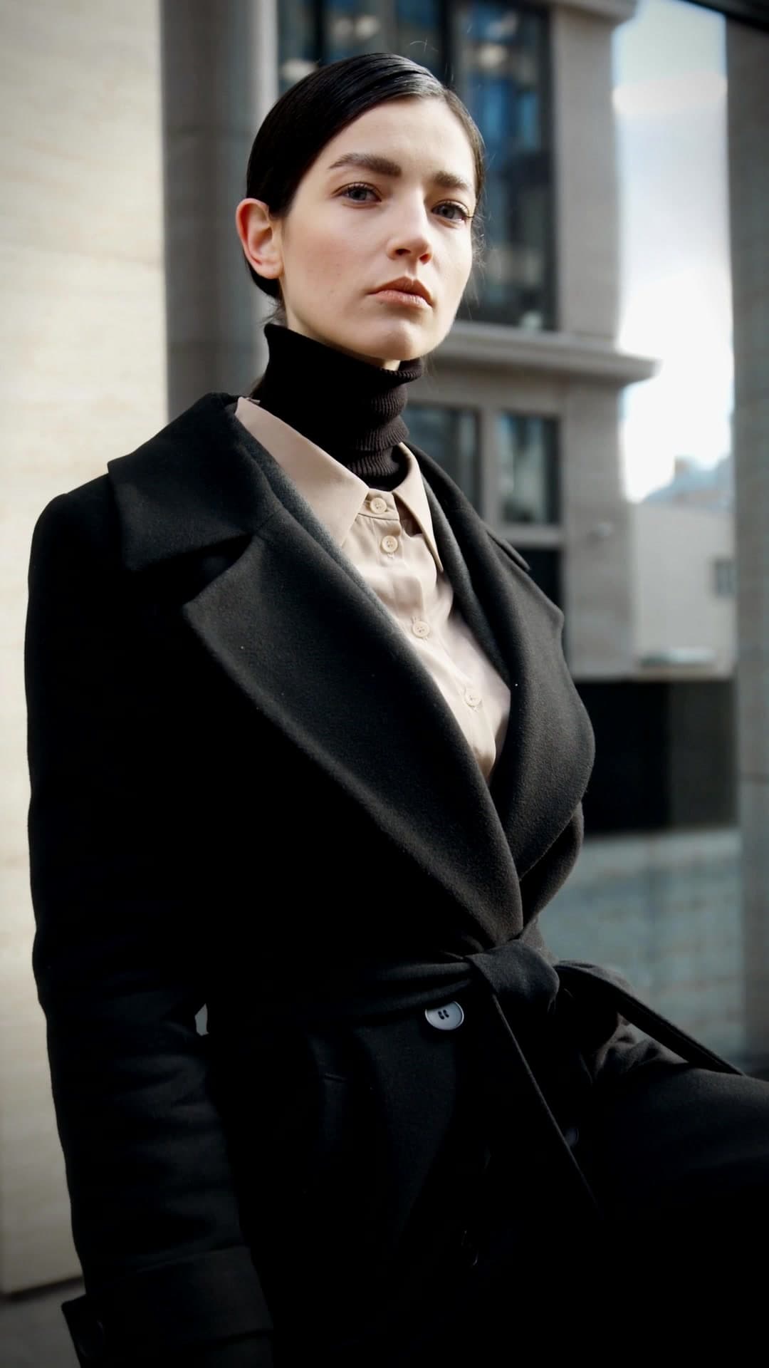 A woman in a black wool coat and turtleneck, the final look of the Own the Elements campaign