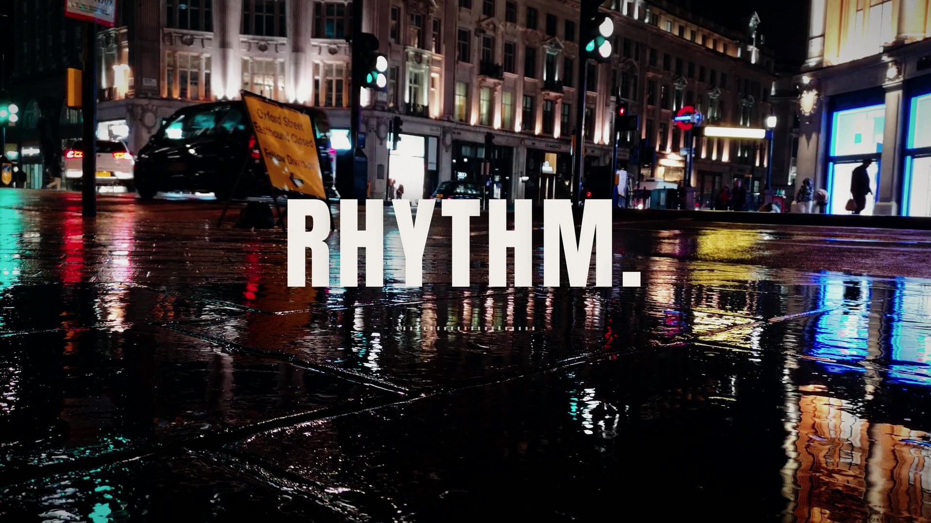 Rain-soaked city street at night lit by neon reflections