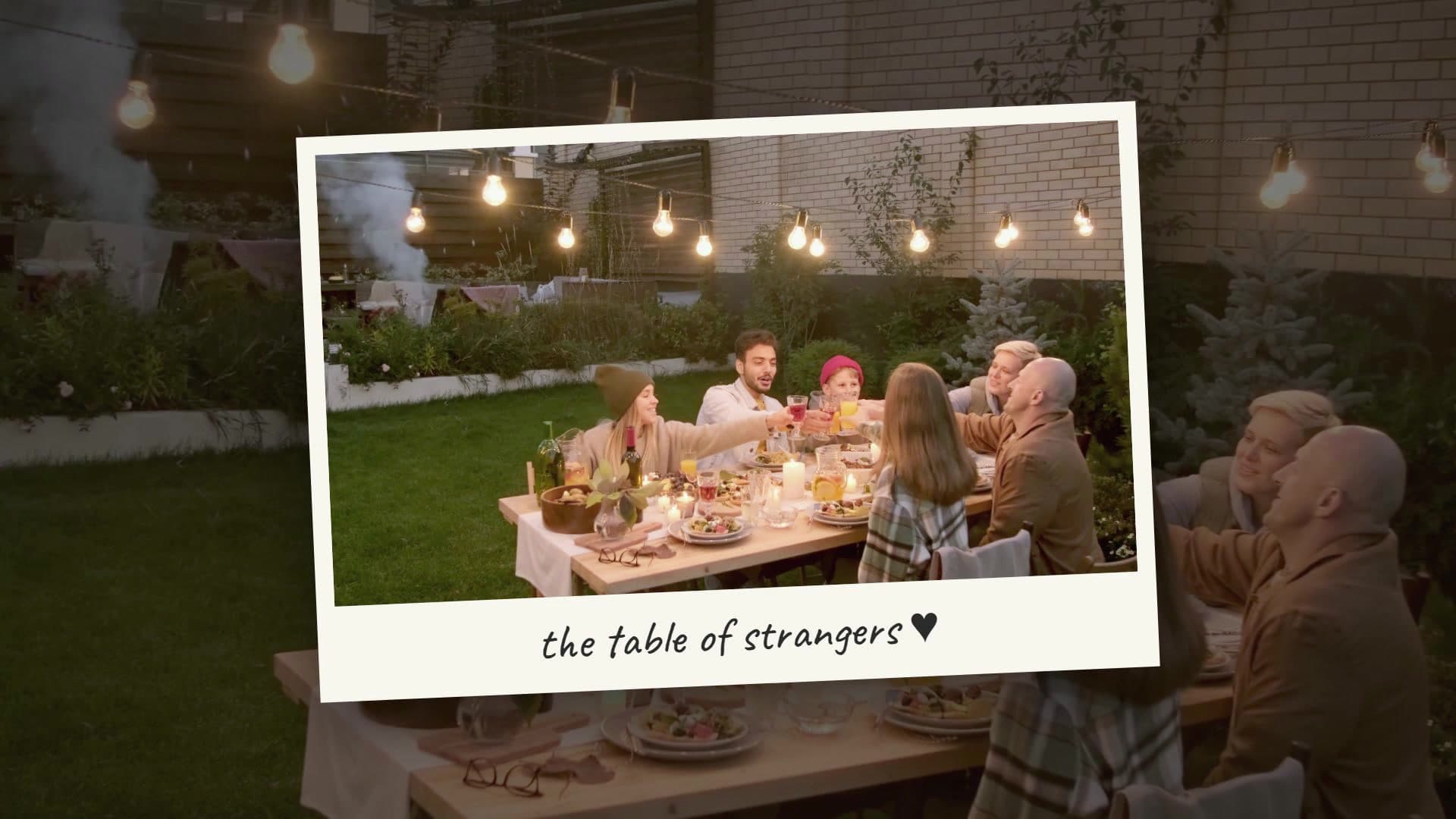 A polaroid frame titled the table of strangers over an outdoor group dinner