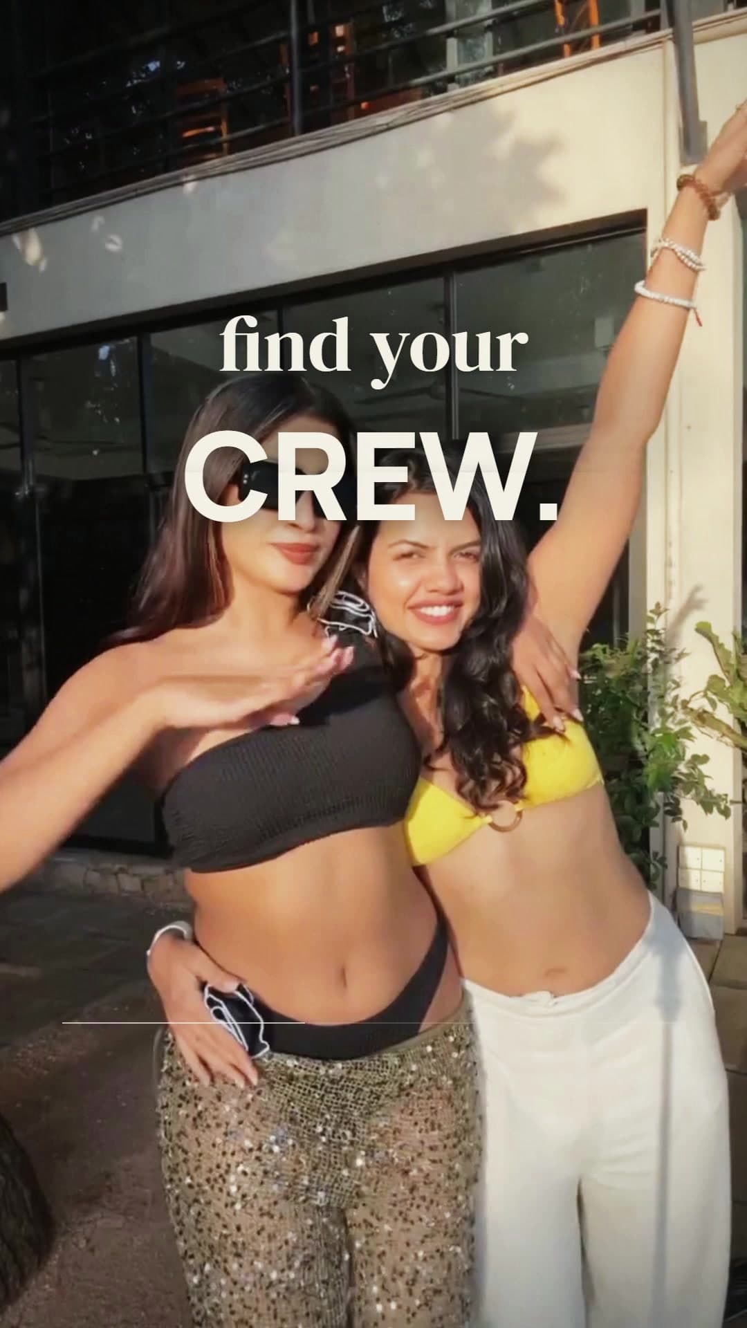 Two friends laughing and posing outside a café under the words find your CREW